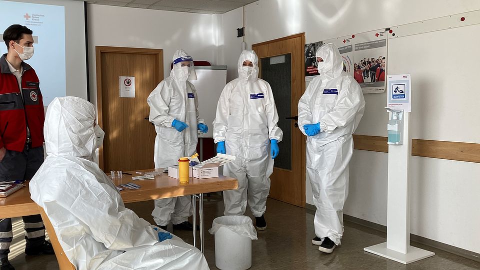 Die Schulungsteilnehmer in Schutzanzügen bei praktischen Übungen